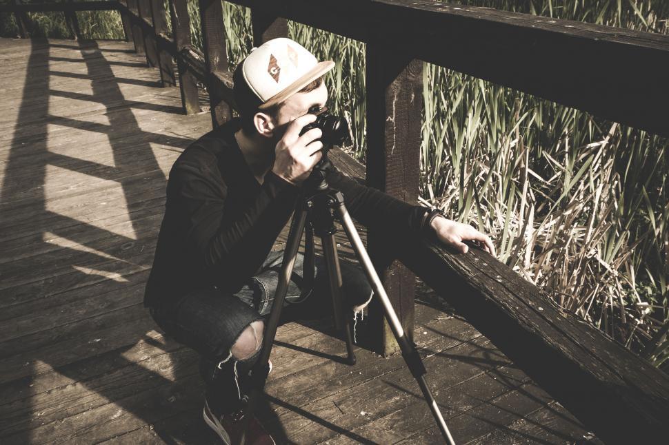 Free Image of Photographer setting up a tripod outdoors 