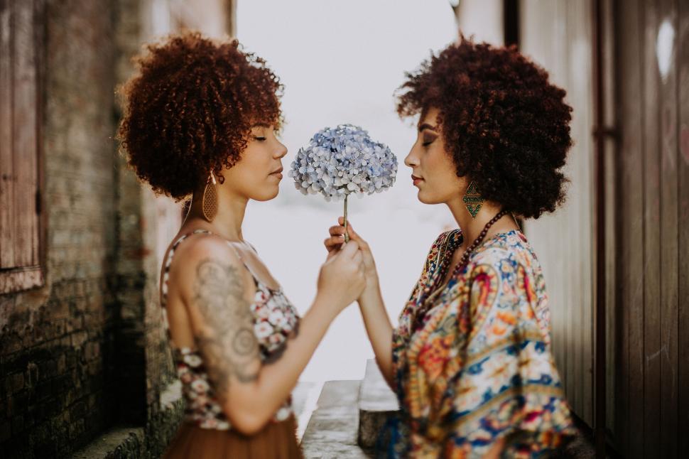 Free Image of Two Women Exchanging Flowers Face to Face 