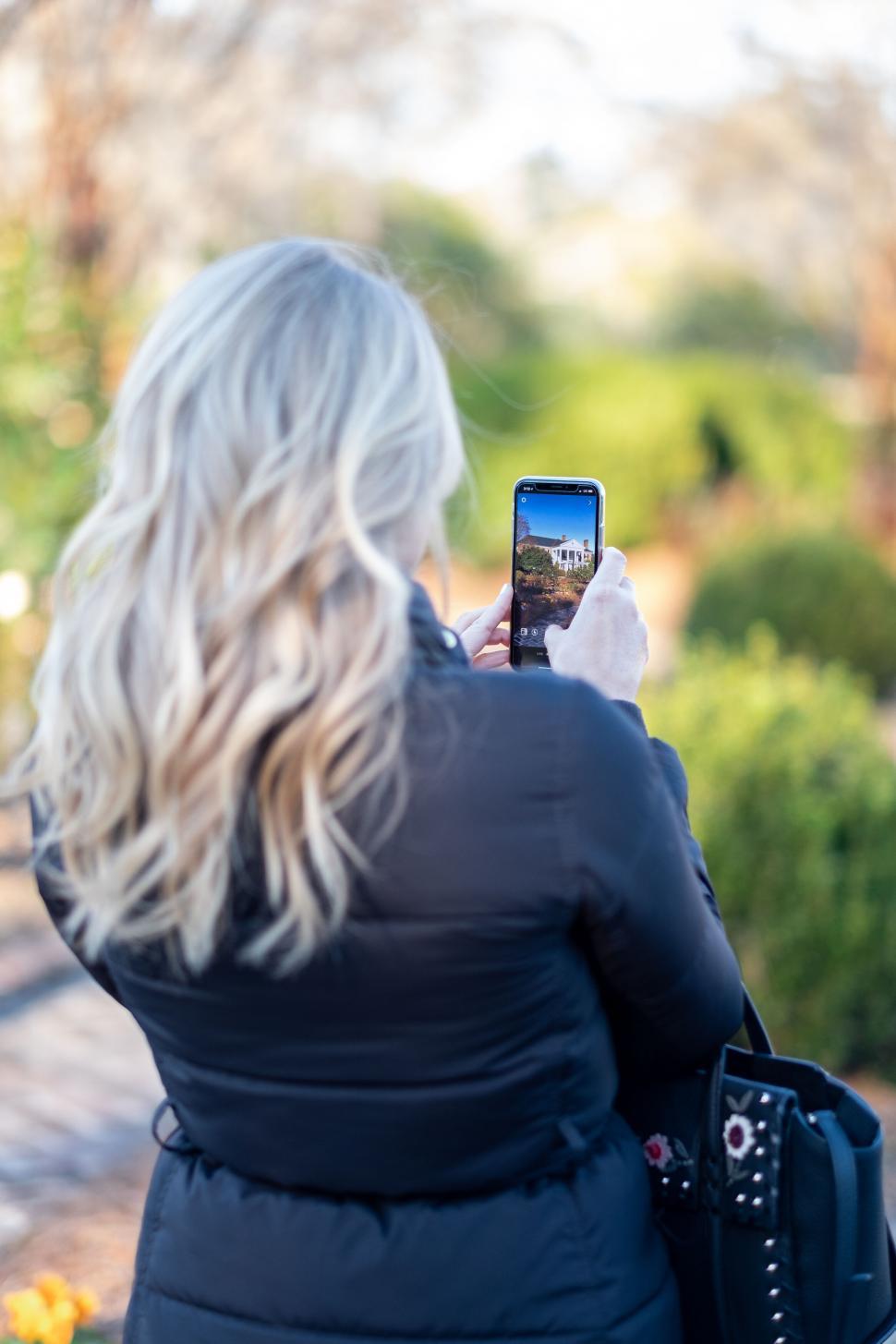 Free Image of Woman capturing garden photo on smartphone 