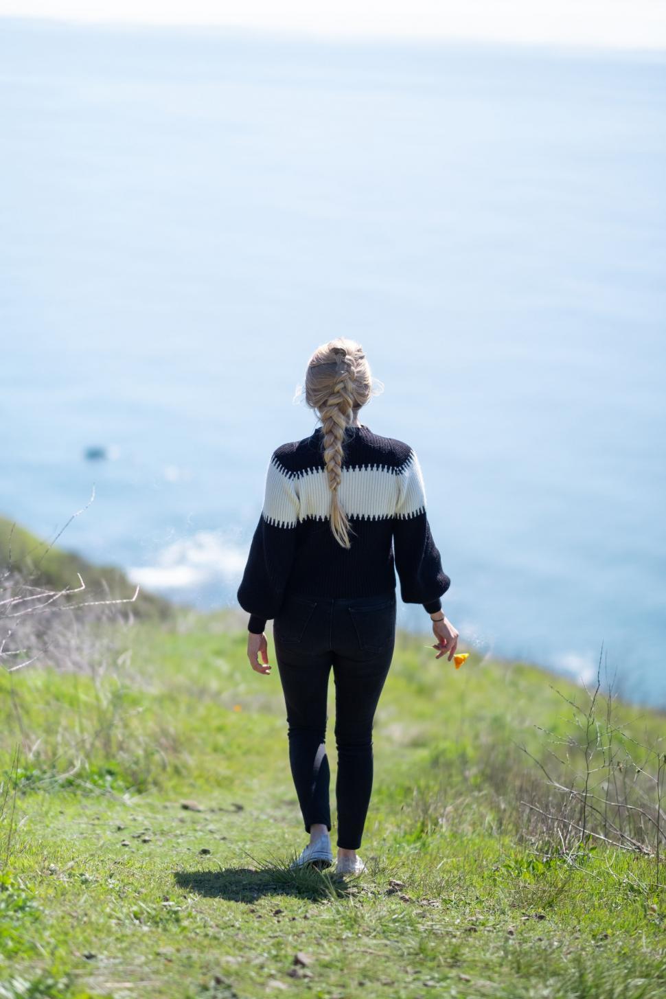 Free Image of Woman walking towards the ocean on a path 