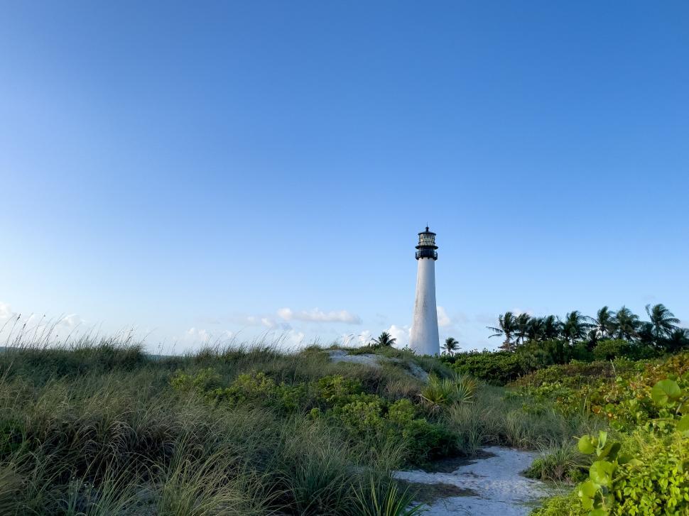 Free Image of Lighthouse amid beach dunes under blue sky 