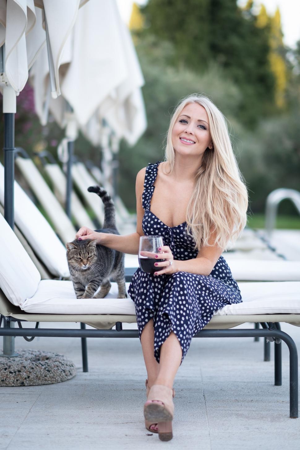 Free Image of Blonde woman smiling with cat and wine 