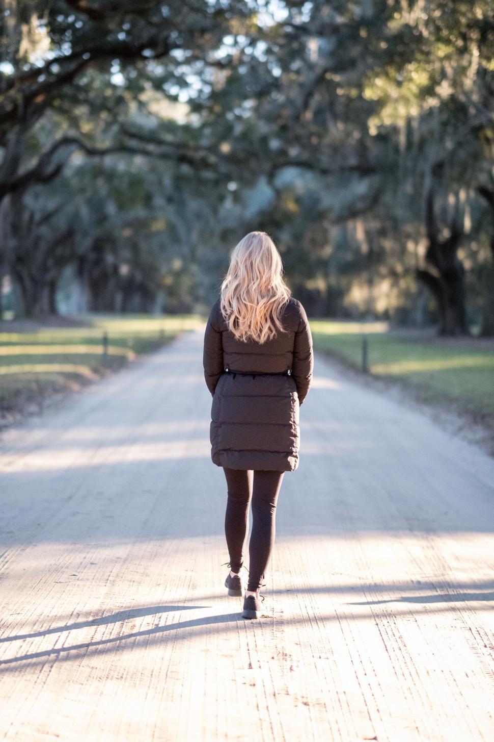 Free Image of Woman walking alone on a country road 