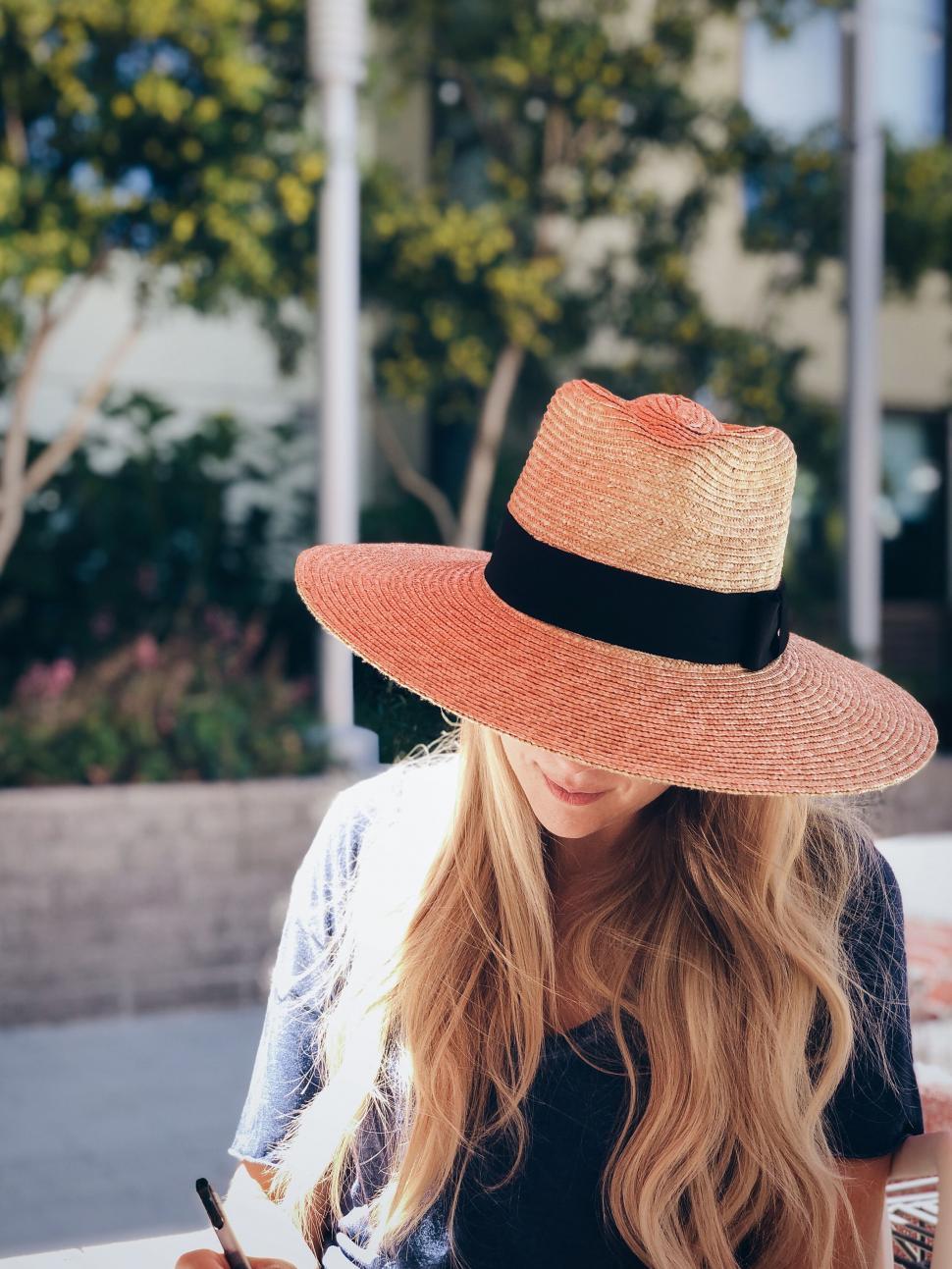 Free Image of Woman in orange straw hat using smartphone 