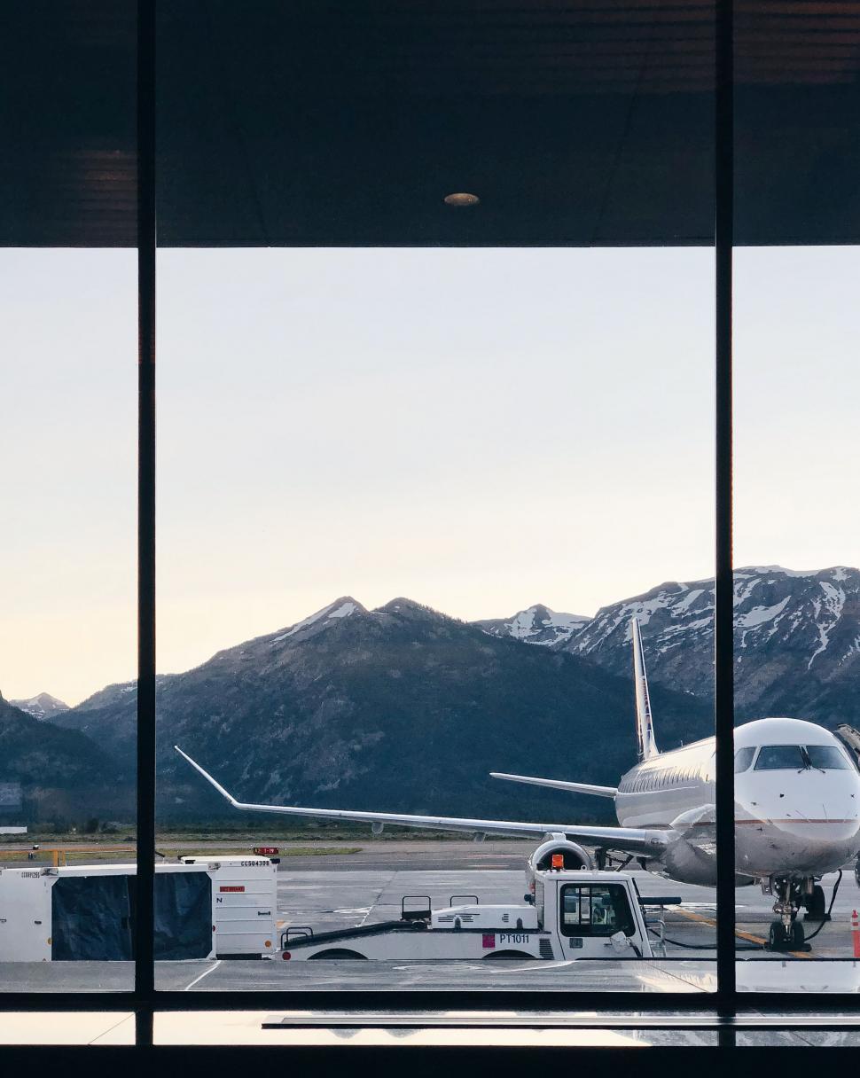Free Image of Airport View with Airplane and Mountain Backdrop 