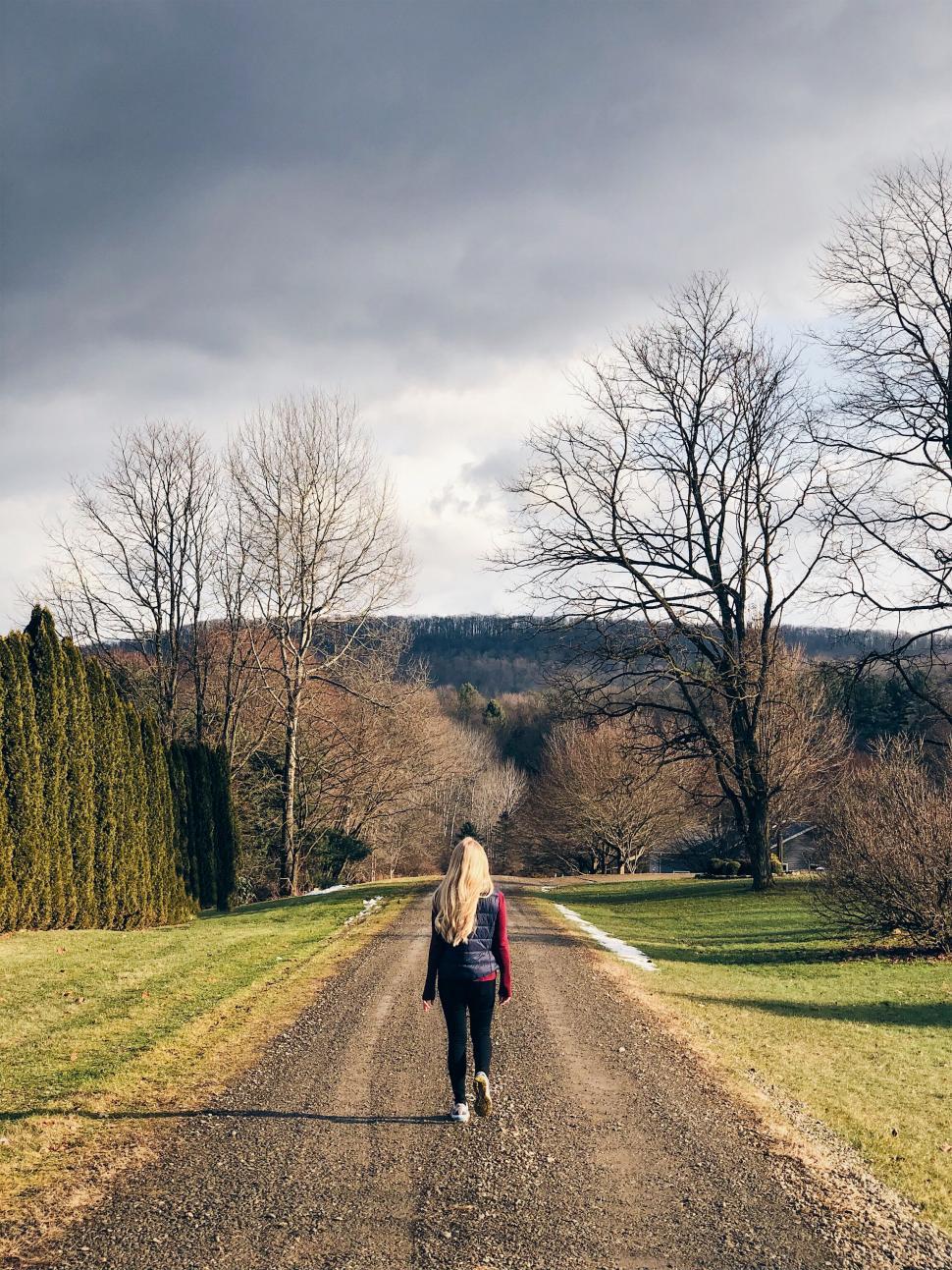 Free Image of Woman walking on a country road in autumn 