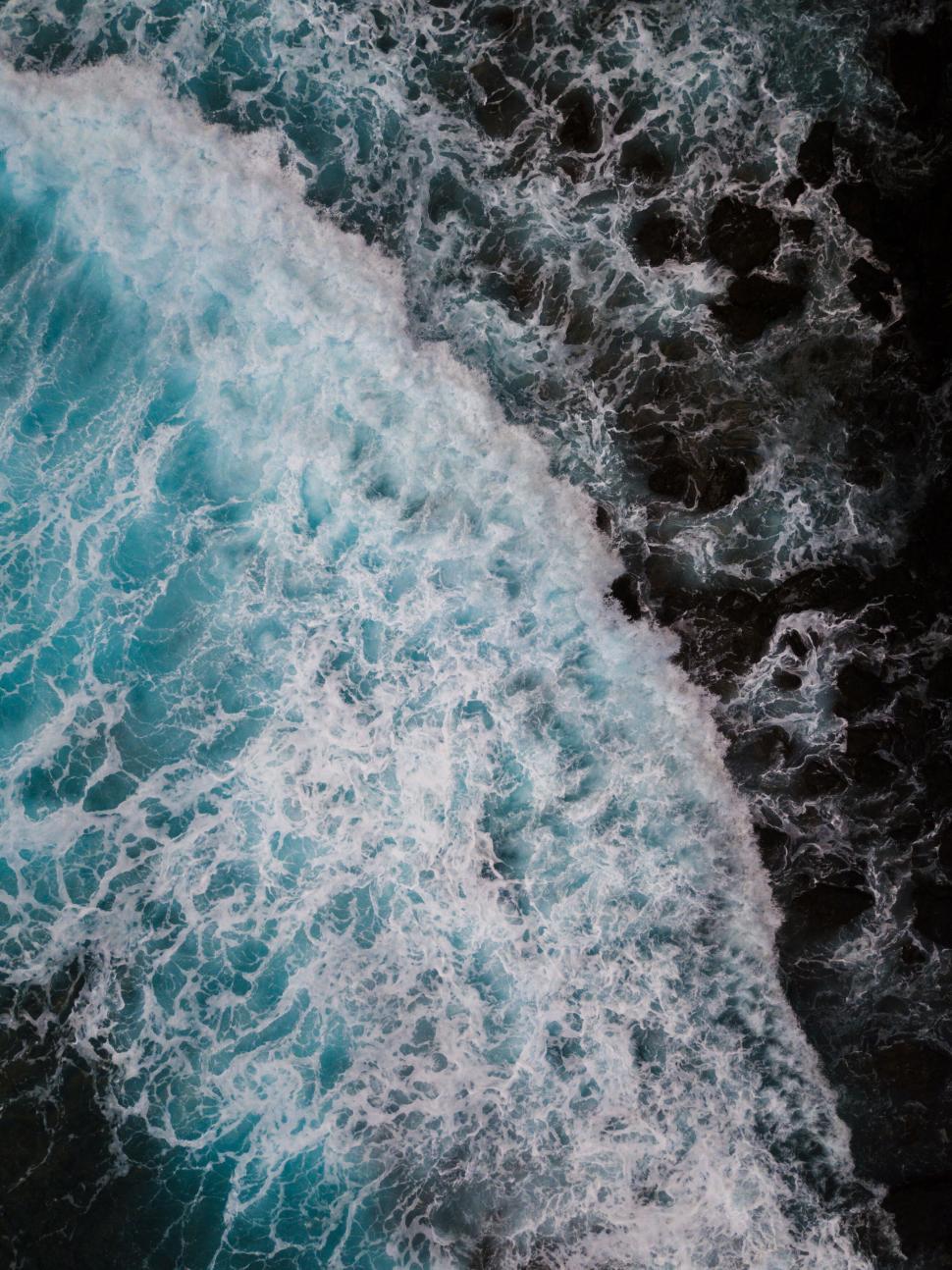 Free Image of Turquoise waves crashing onto dark rocks 