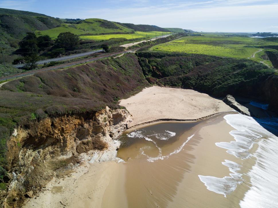 Free Image of Aerial view of coastline and green hills 