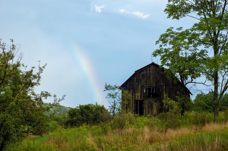 Free Image of Old barn under a rainbow in a lush field 