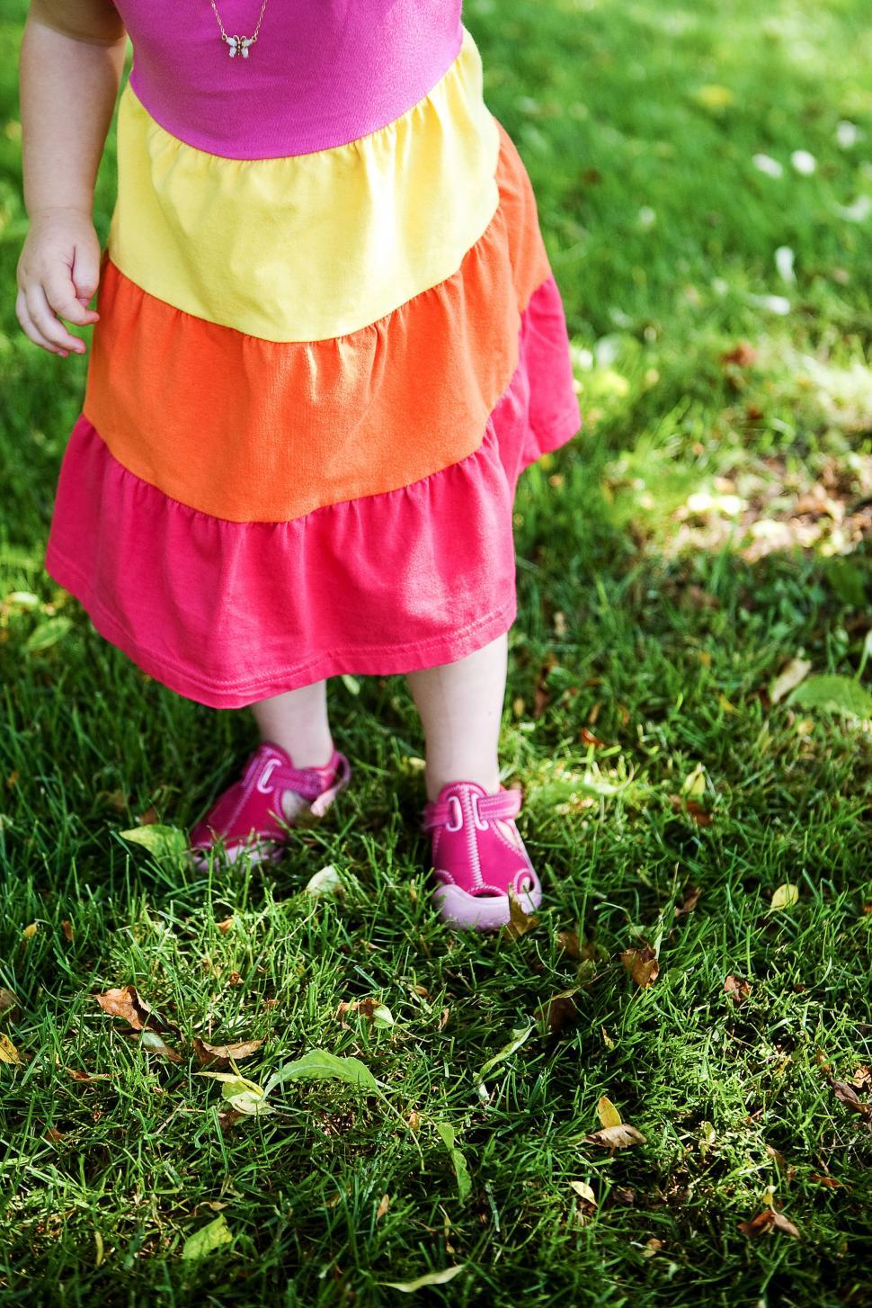 Free Image of Toddler in a multicolor dress on grass 
