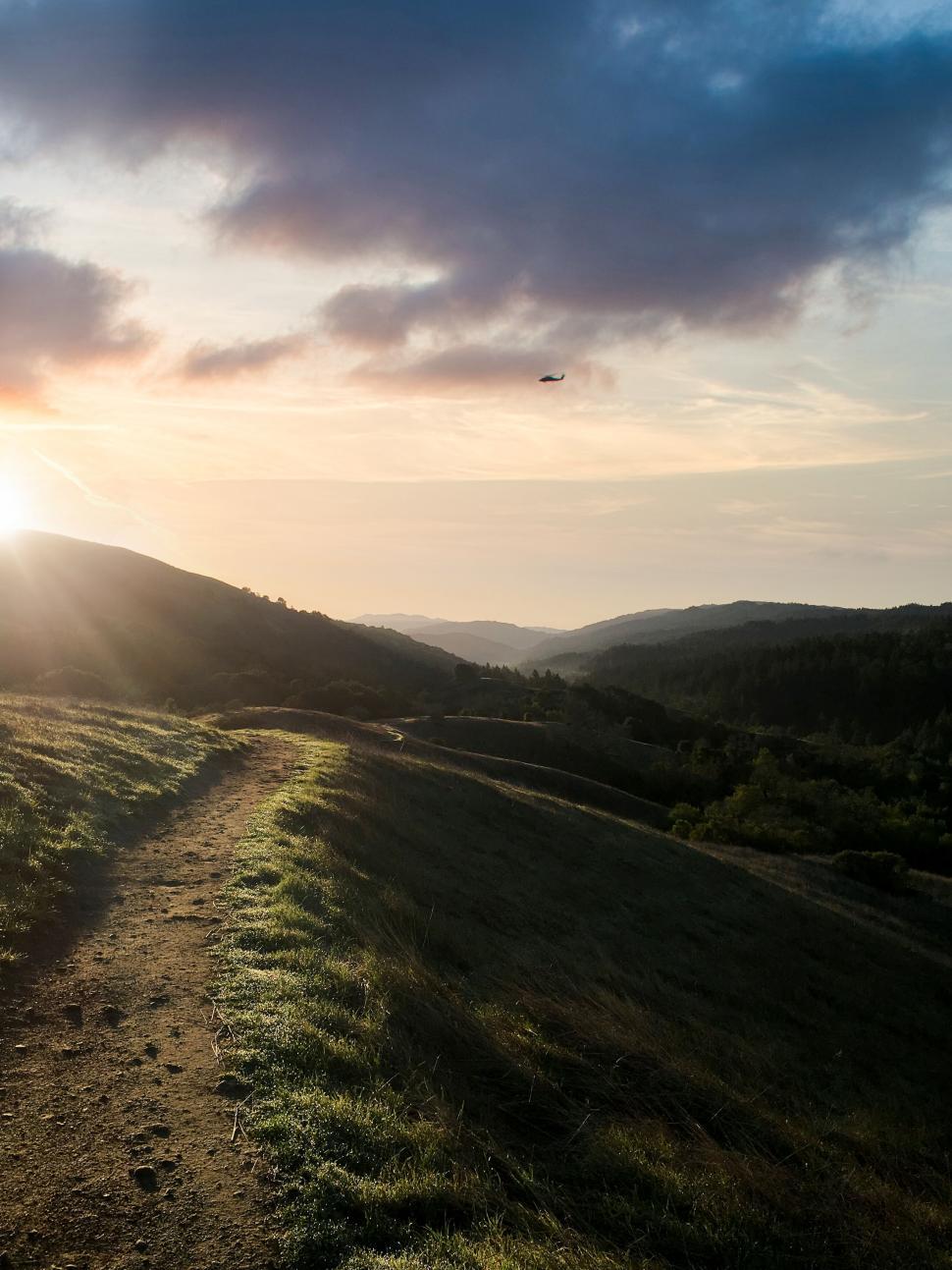 Free Image of Sunrise over hills with winding path 