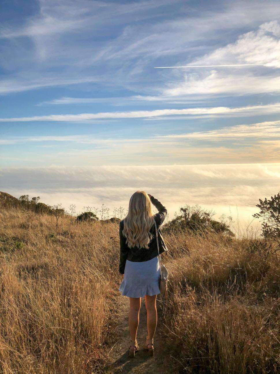 Free Image of Woman gazing at overcast sky on a trail 