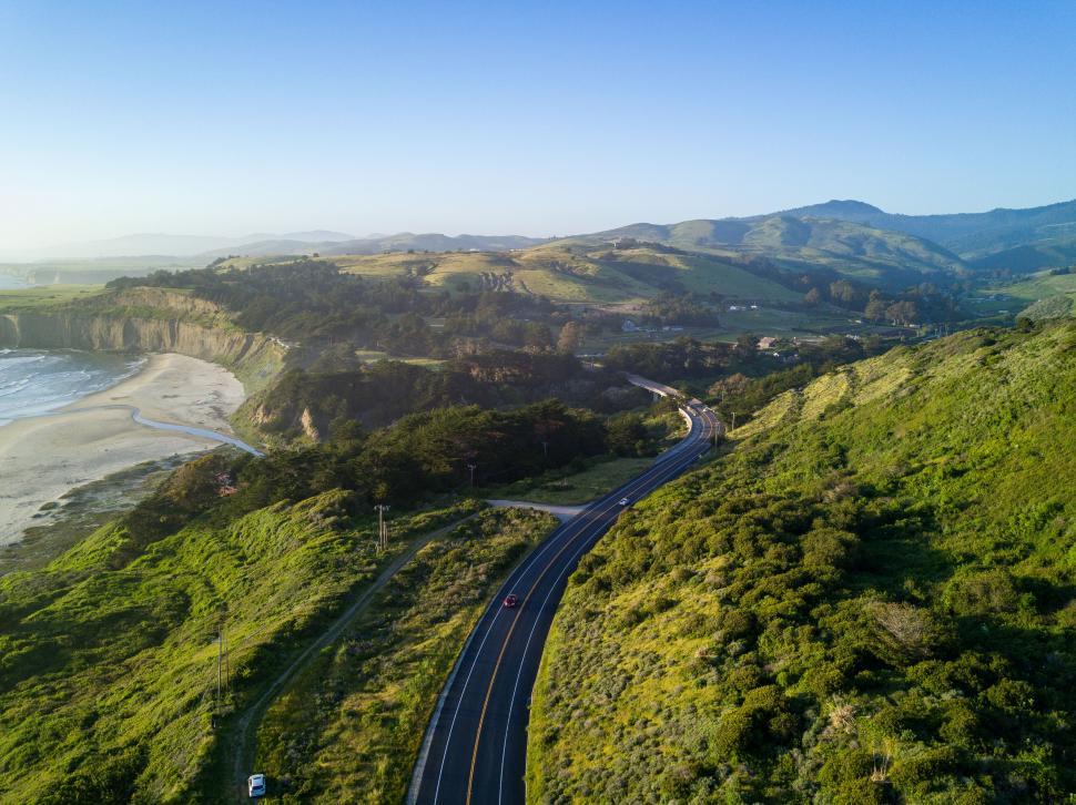 Free Image of Aerial view of coastal road winding through hills 