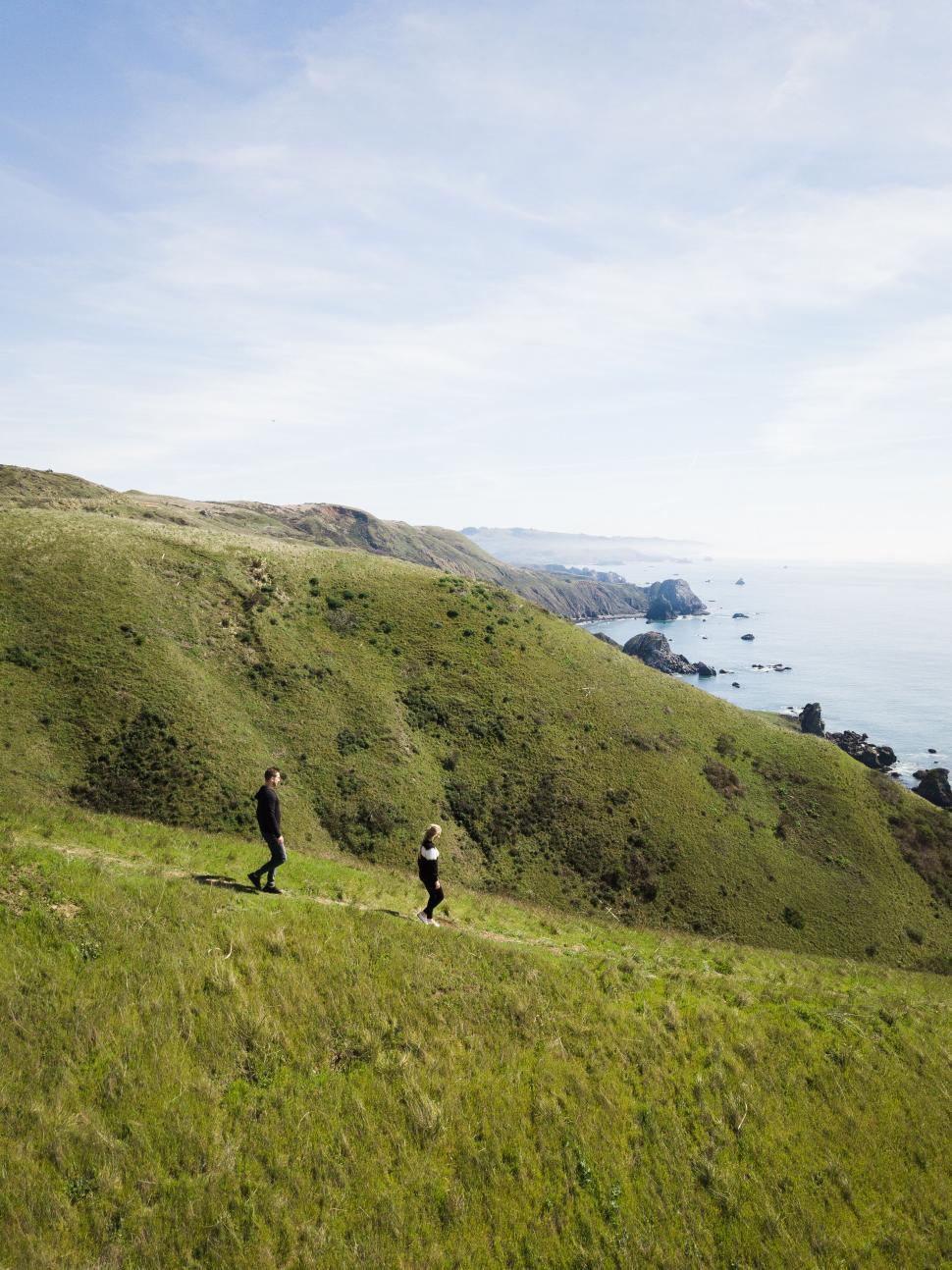 Free Image of Two people hiking on a coastal trail 