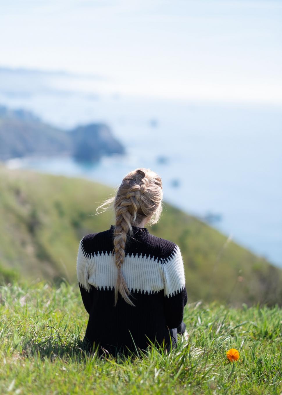 Free Image of Woman gazing at the ocean from a hill 