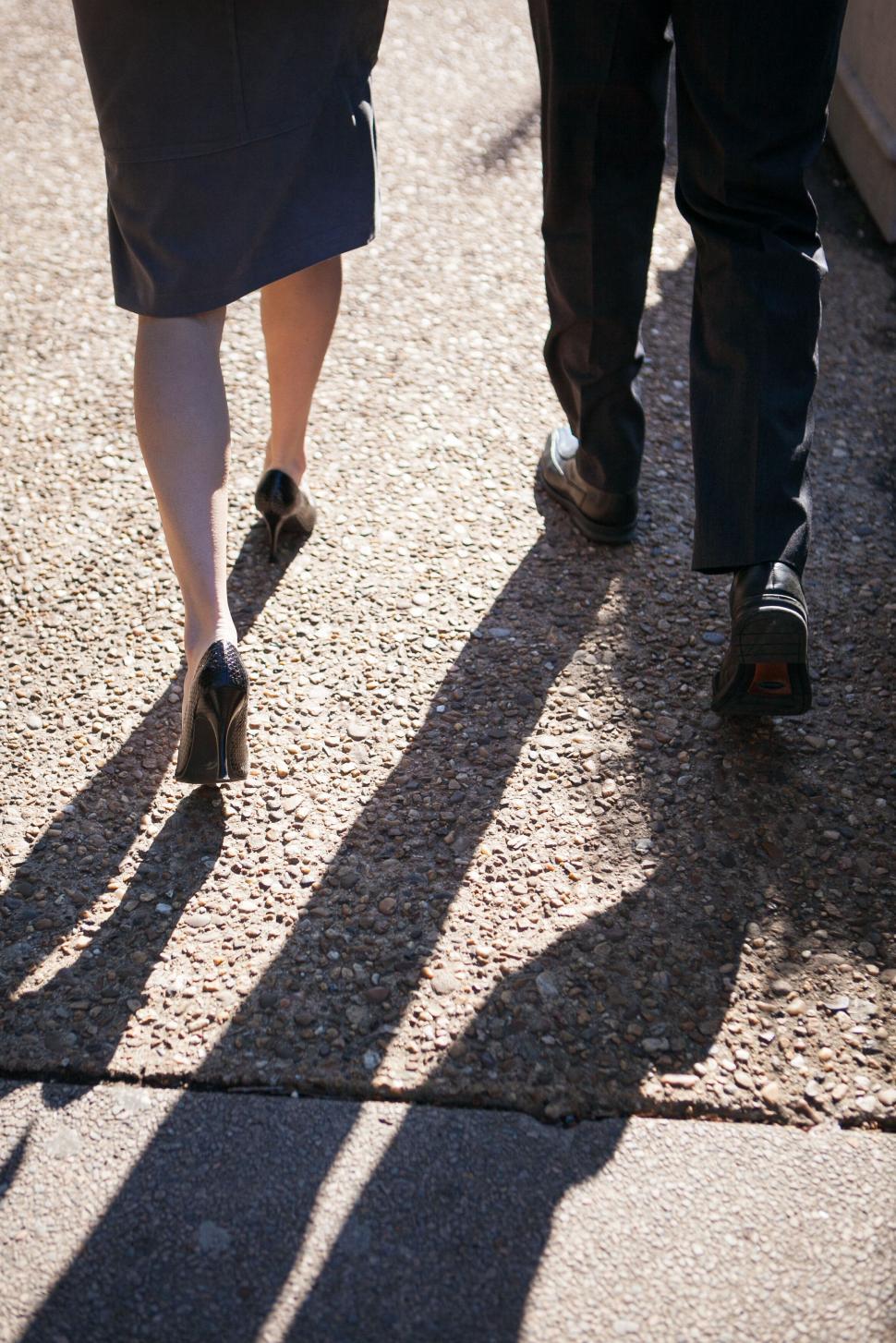 Free Image of Walking couple s shadow on a cobblestone path 