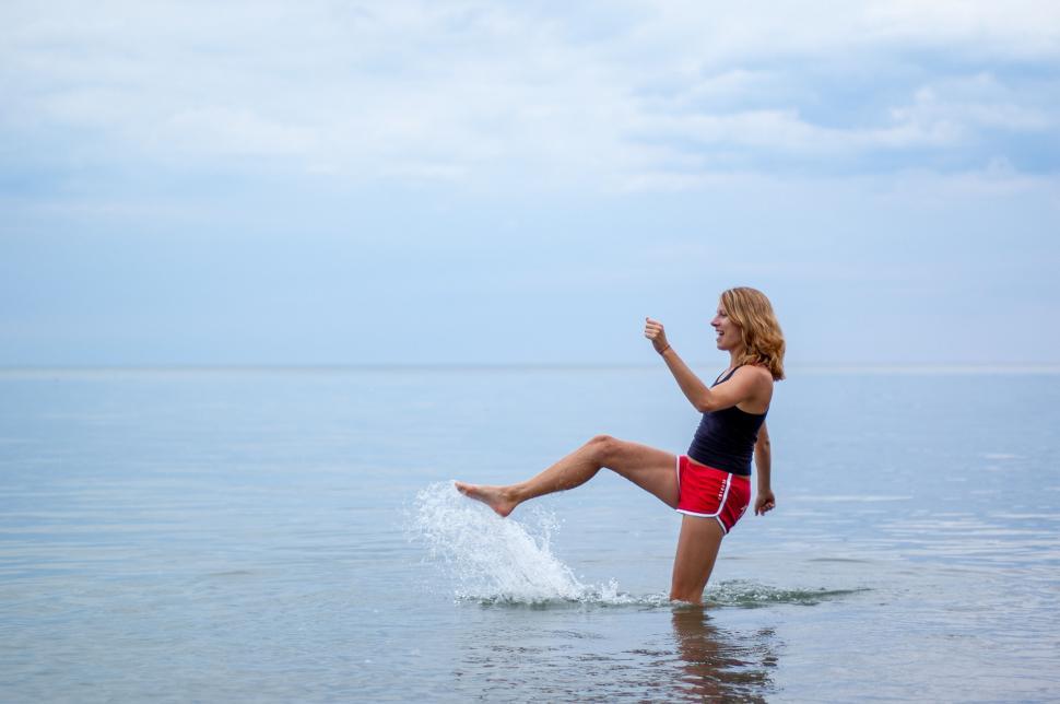 Free Image of Woman splashing water on beach day 
