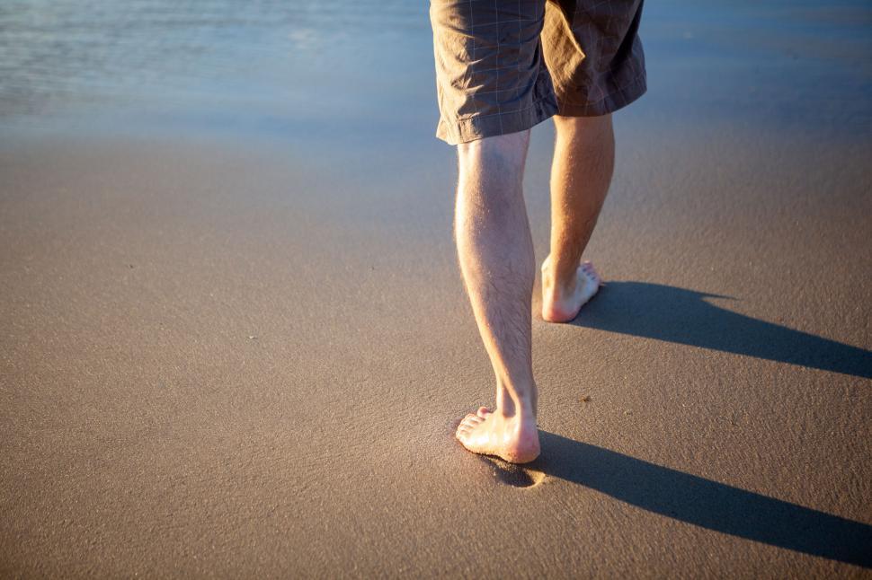 Free Image of Man walking on sandy beach at sunset 