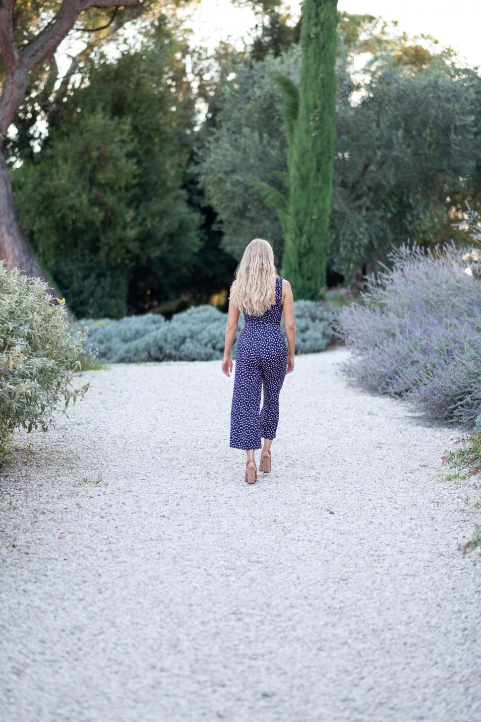Free Image of Woman walking through garden in summer dress 