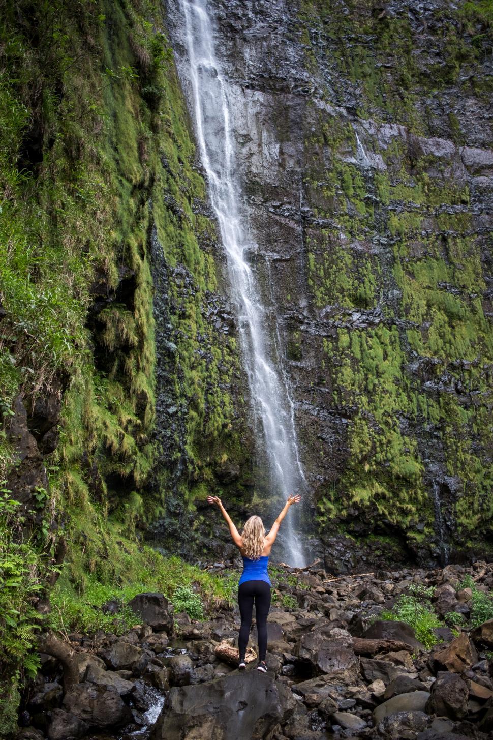 Free Image of Waterfall with a woman raising arms 