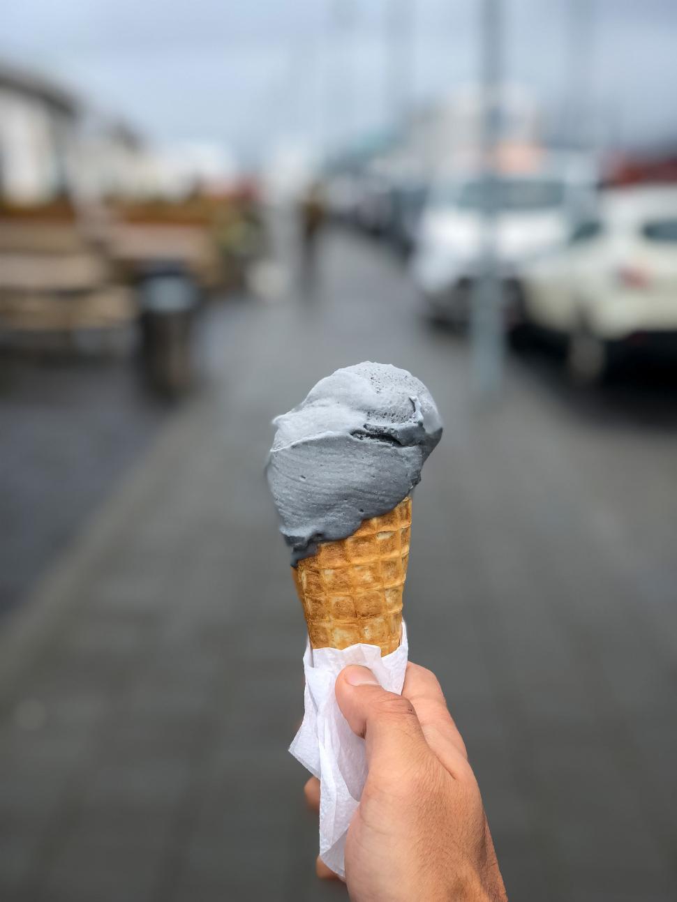 Free Image of Hand holding a black ice cream cone 