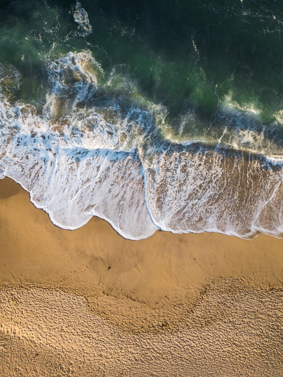Free Image of Aerial view of ocean waves on sandy beach 
