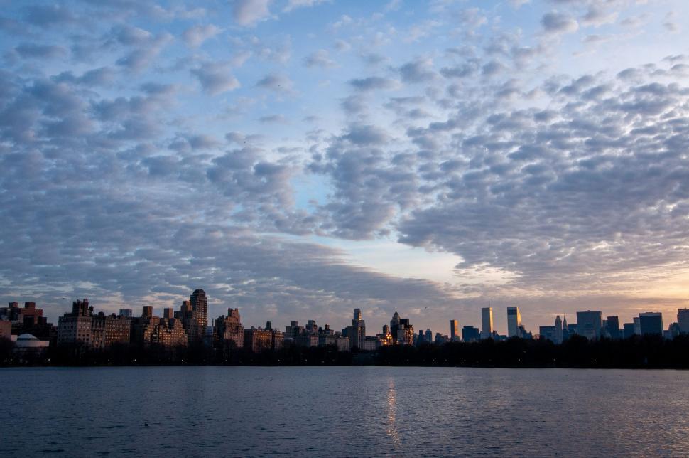 Free Image of Skyline of a city during a sunset with scattered clouds 
