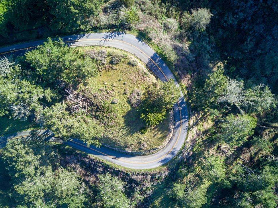 Free Image of Aerial view of a winding road through a forest 