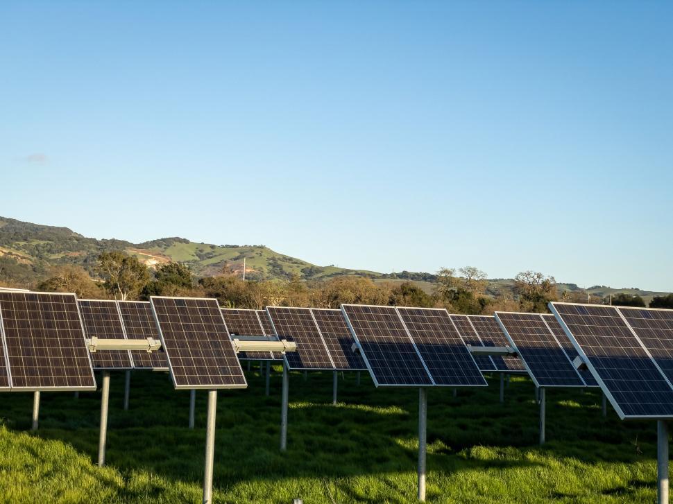 Free Image of Solar panels in green field with hills 