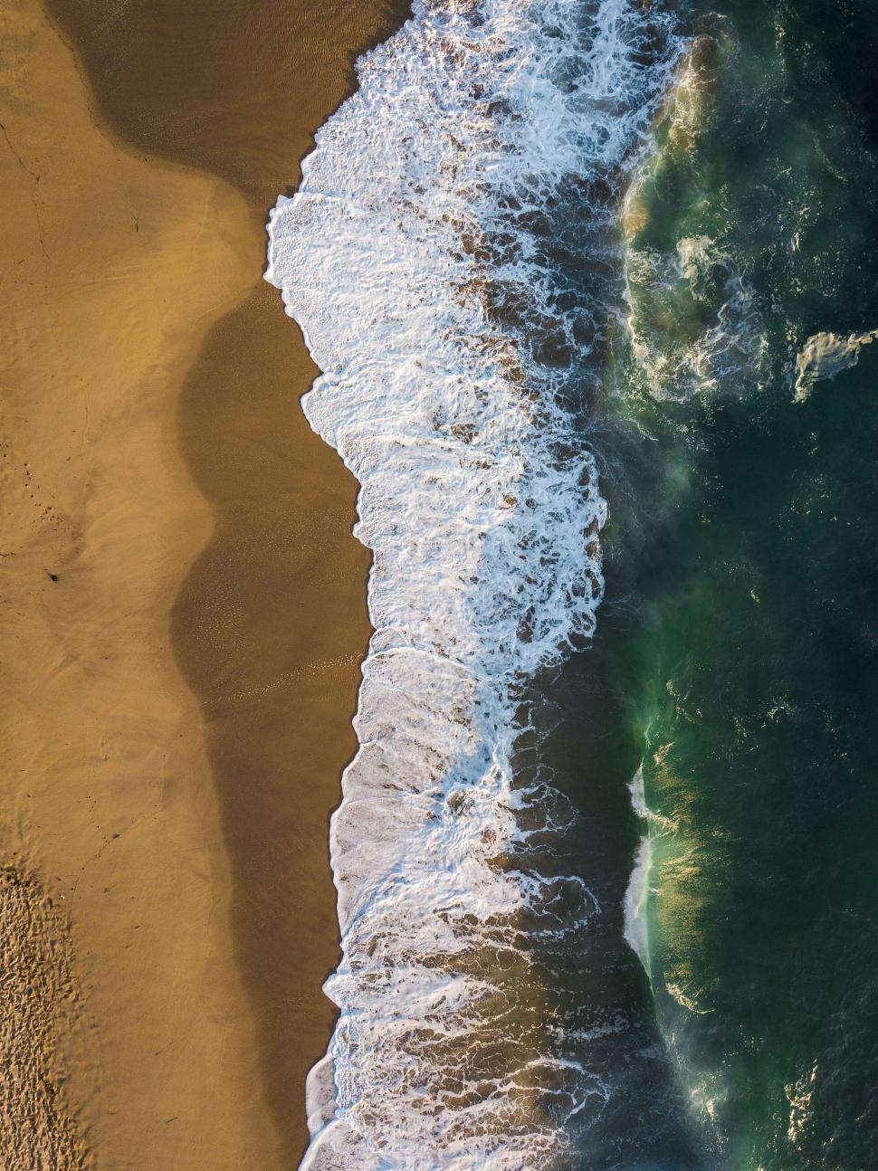Free Image of Aerial shot of beach with waves and sand 