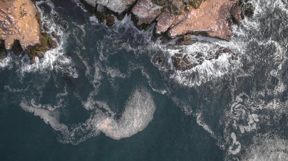 Free Image of Overhead view of rocky coast and sea foam 