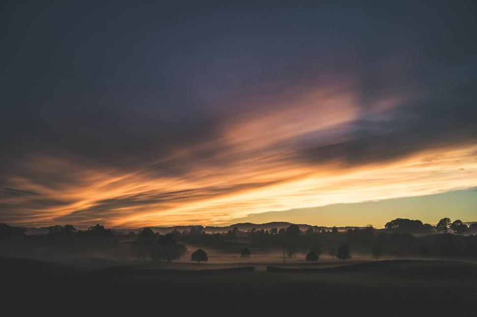 Free Image of Dramatic sunset over a misty rural landscape 