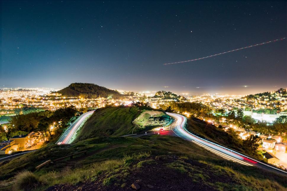 Free Image of Nighttime cityscape with light trails and stars 