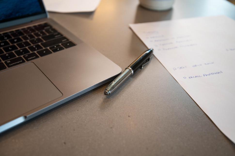 Free Image of Close-up of a laptop with pen and paper 