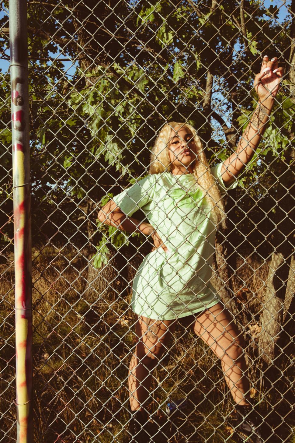 Free Image of Woman dancing by chain-link fence 