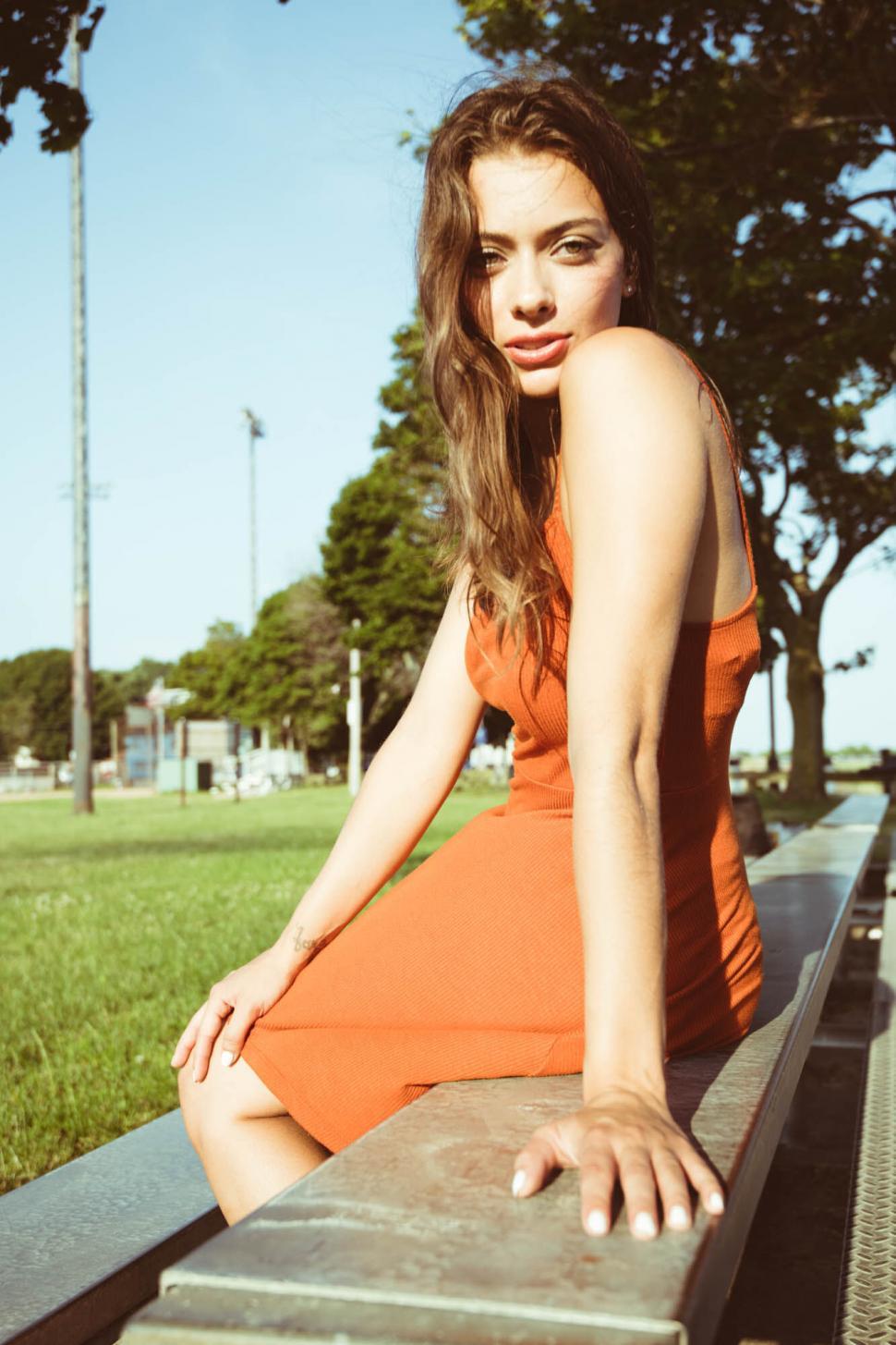 Free Image of Woman in orange dress by the waterfront 
