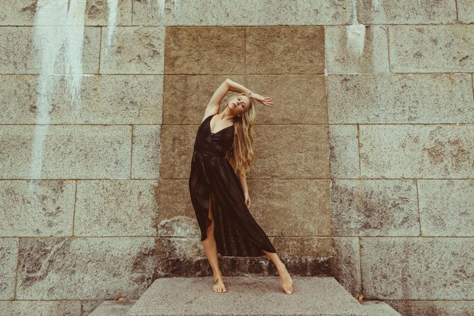 Free Image of Woman dancing in front of textured wall 
