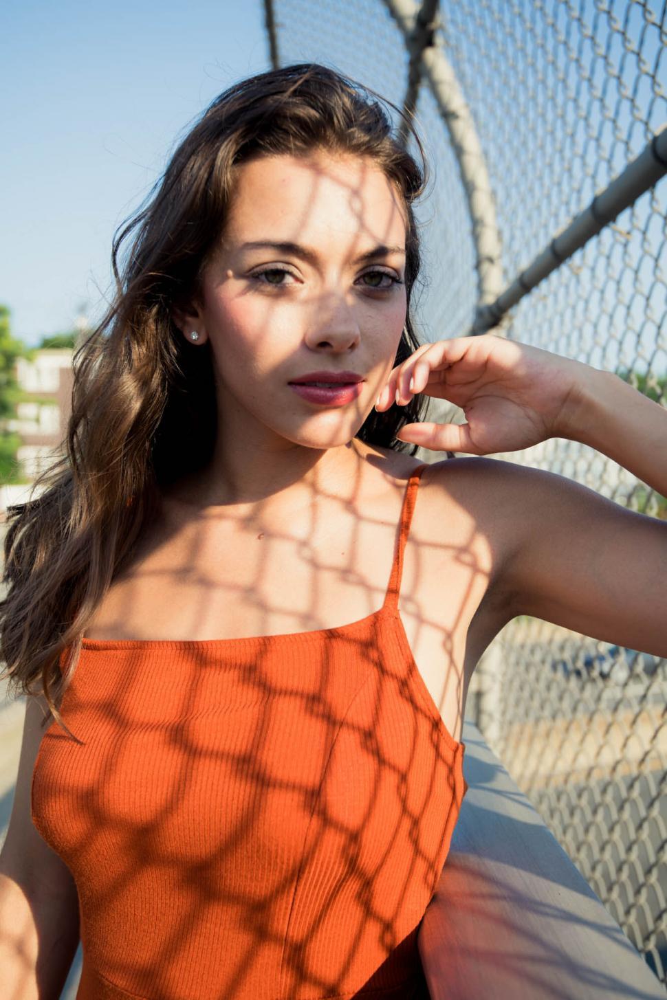 Free Image of Close-up of woman in orange by chain fence 
