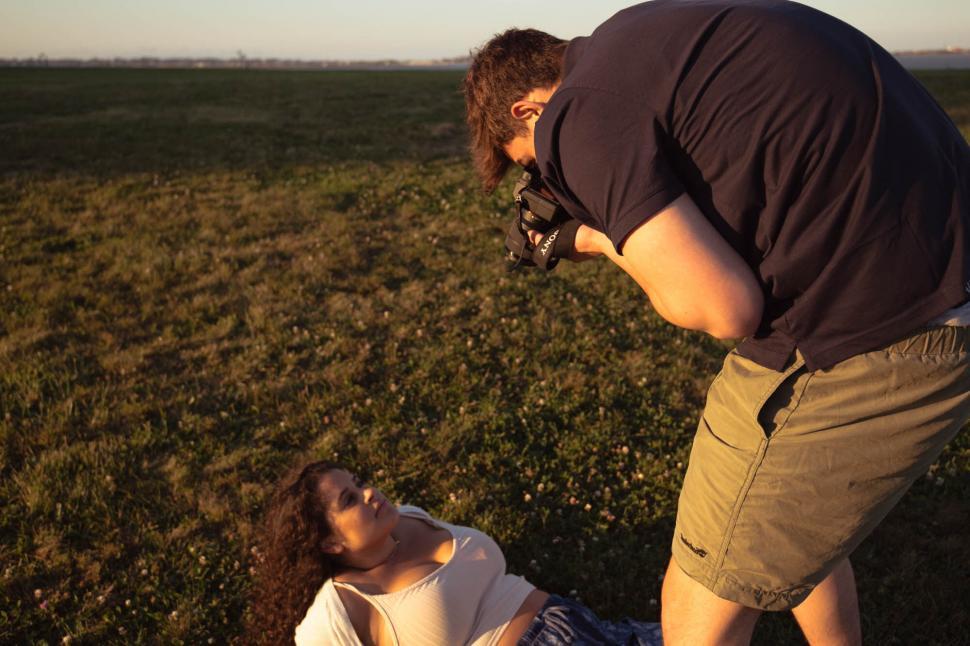 Free Image of Man photographing a woman in a field 