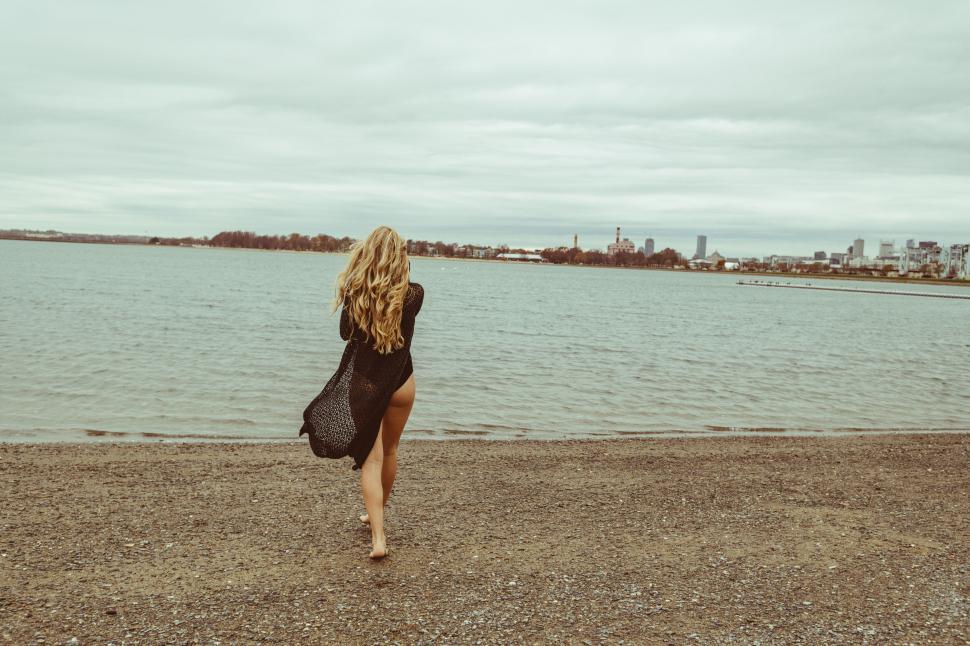 Free Image of Woman walking on beach in autumnal setting 