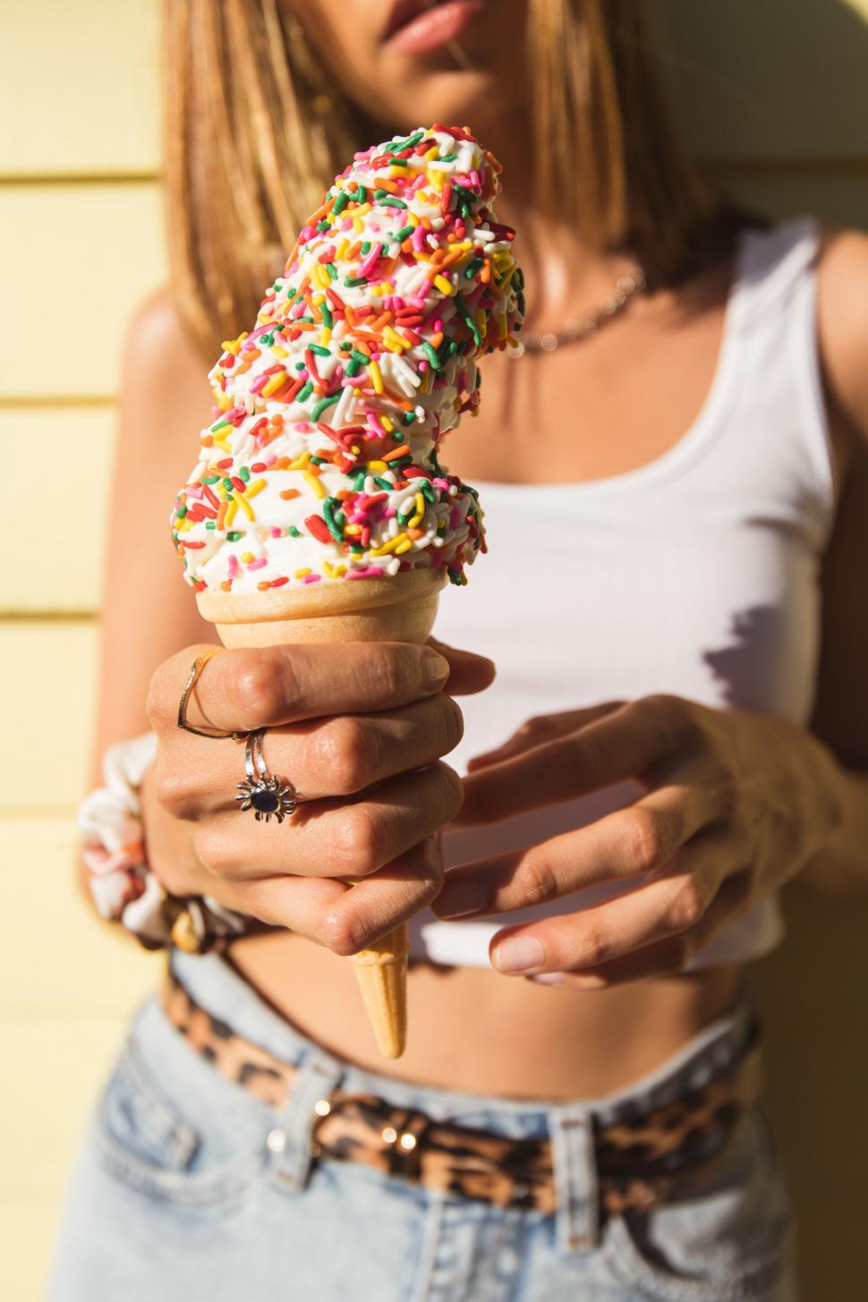 Free Image of Woman holding a sprinkled ice cream cone closeup 