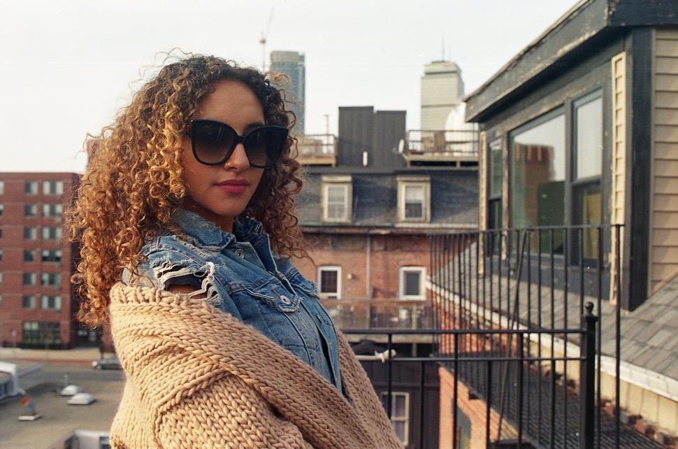 Free Image of Woman on rooftop wearing denim and knitwear 