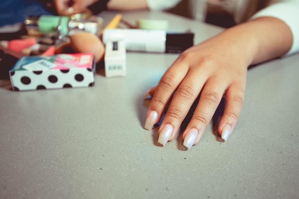 Free Image of Hand with manicured nails and various beauty products 