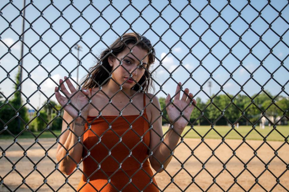 Free Image of Woman peering through fence with anticipation 