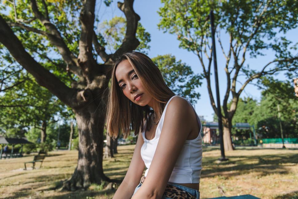 Free Image of Young woman sitting in a park on a sunny day 
