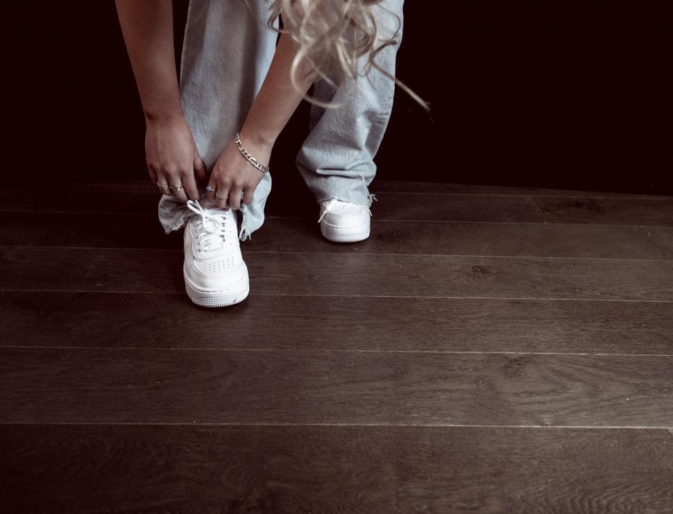 Free Image of Person tying shoelaces on white sneakers 