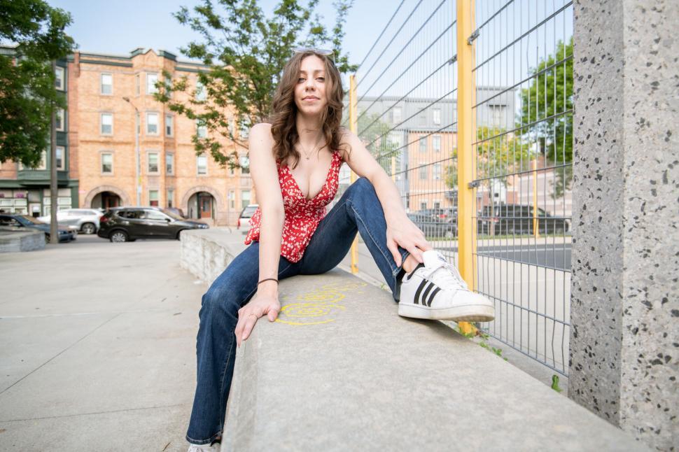 Free Image of Casually dressed woman sitting on ledge 