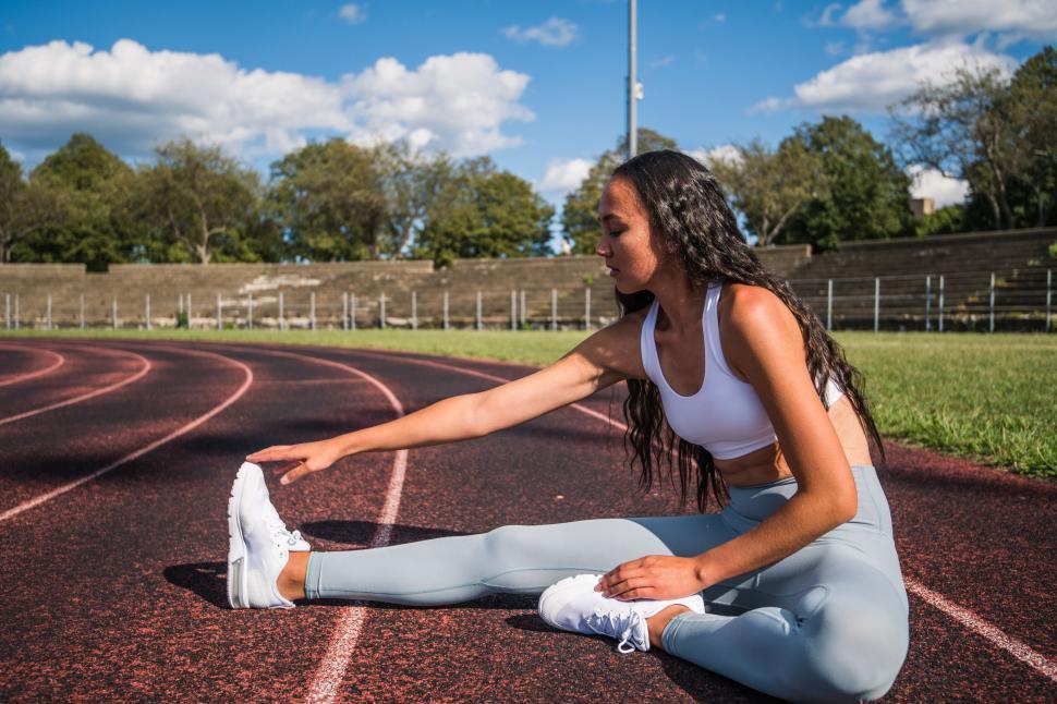 Free Image of Woman stretching on track field in athletic wear 