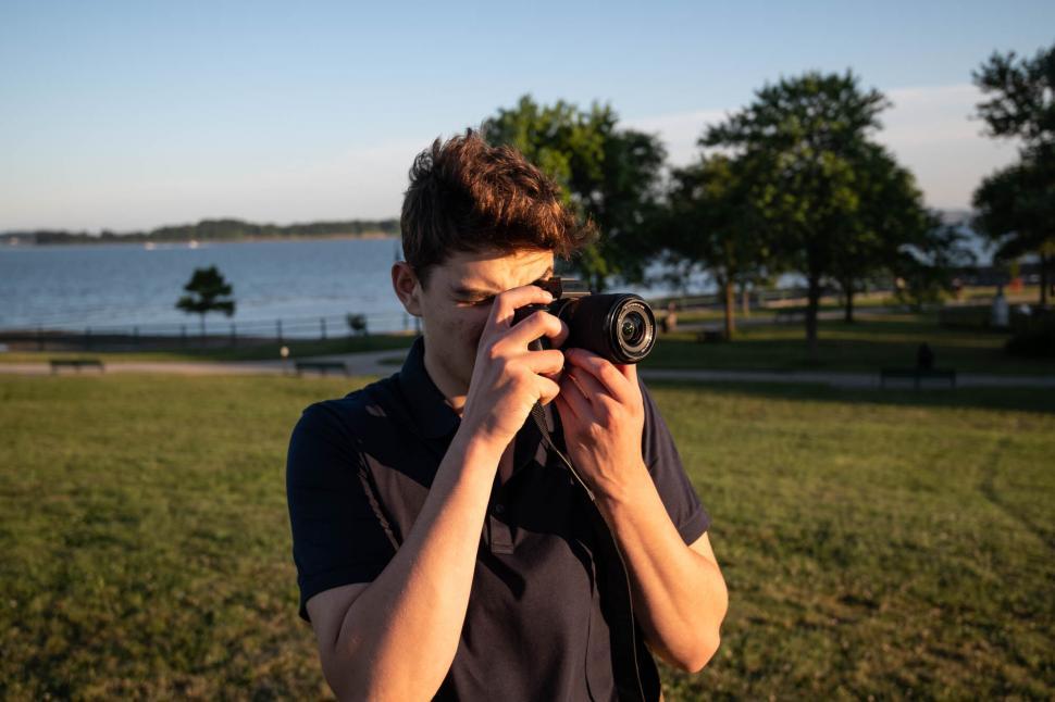 Free Image of Young man holding a camera to face at park 