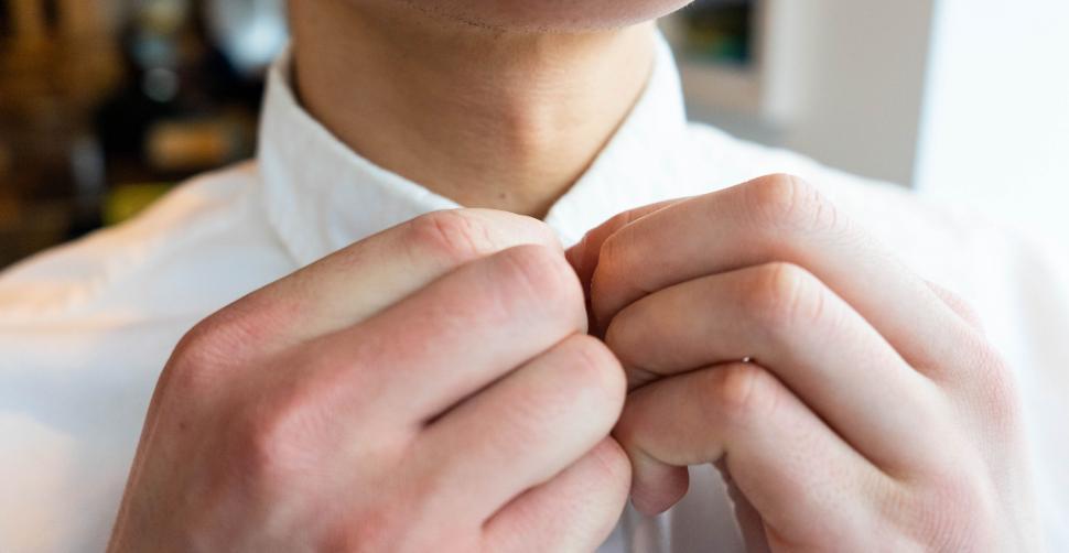 Free Image of Close-up of a man buttoning a white shirt 
